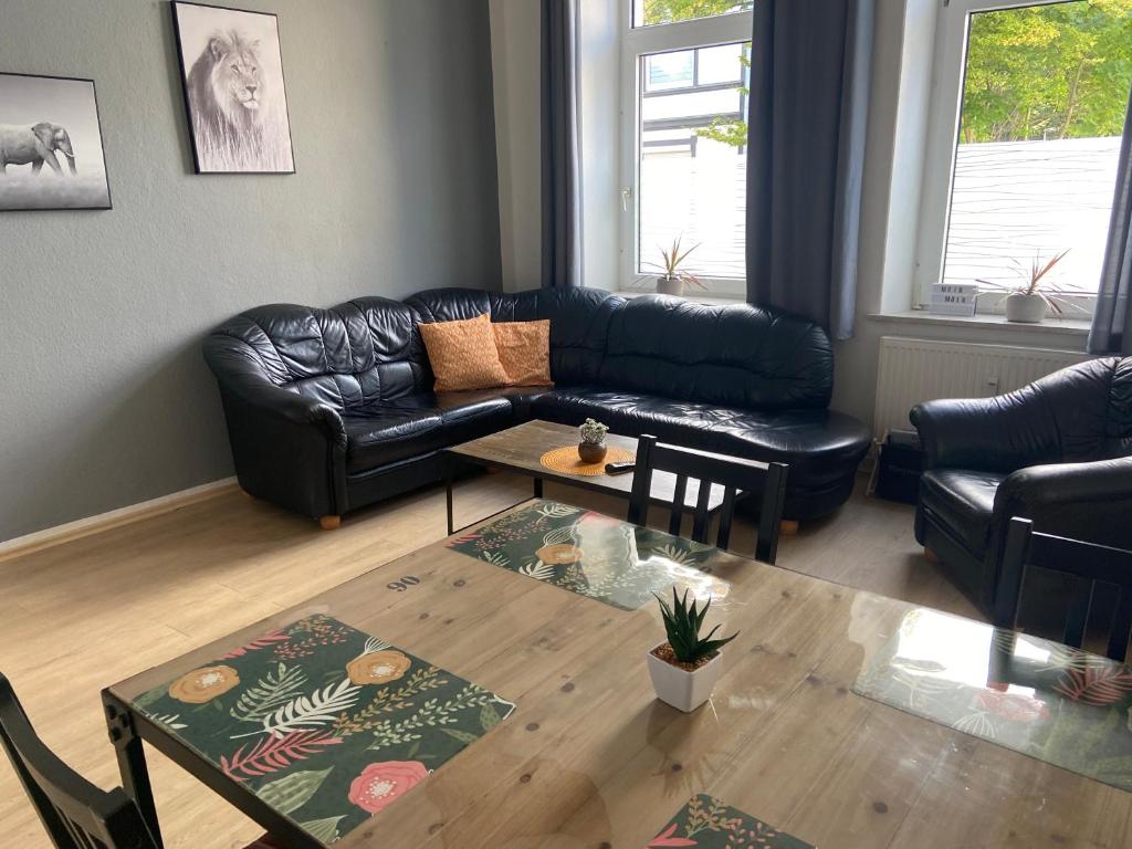 a living room with a black leather couch and a table at Doedelmoker in Wilhelmshaven