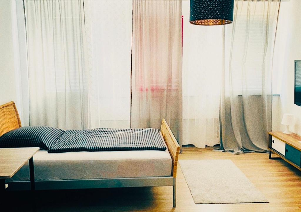 Bett in einem Zimmer mit Vorhängen und einem Tisch in der Unterkunft LINZ bellavista Studio-Apartment Landstraße in Linz