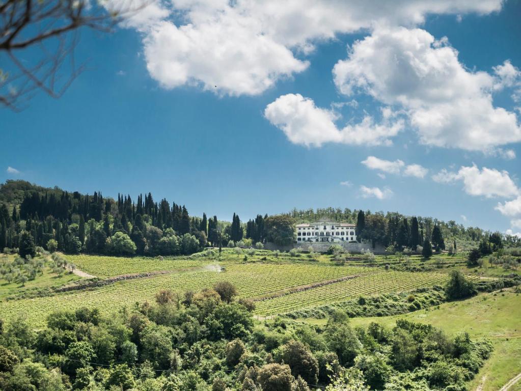 een huis op een heuvel in het midden van een veld bij Villa Vistarenni in Gaiole in Chianti