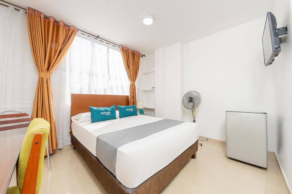 a bedroom with a bed and a mirror and a window at Ayenda Ambeima in Ibagué