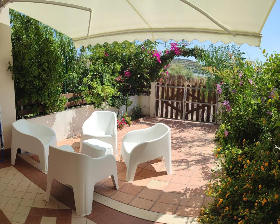 un patio esterno con sedie bianche e fiori di Le Torrette di Anna - Tropea a Briatico