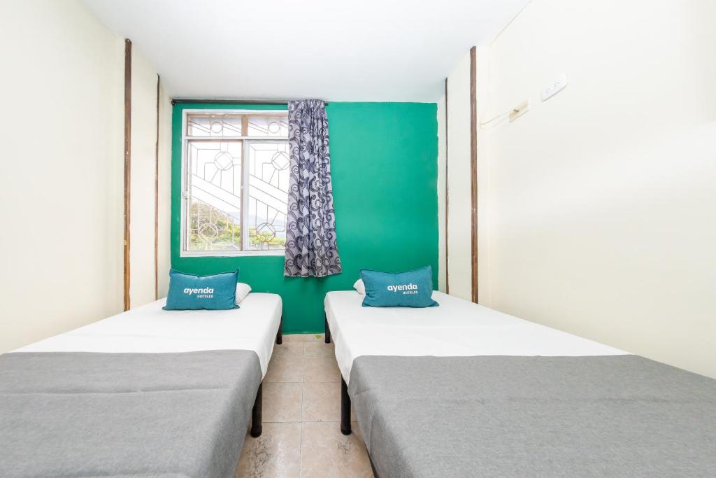 two beds in a room with a green wall at Ayenda Danilo in Ibagué