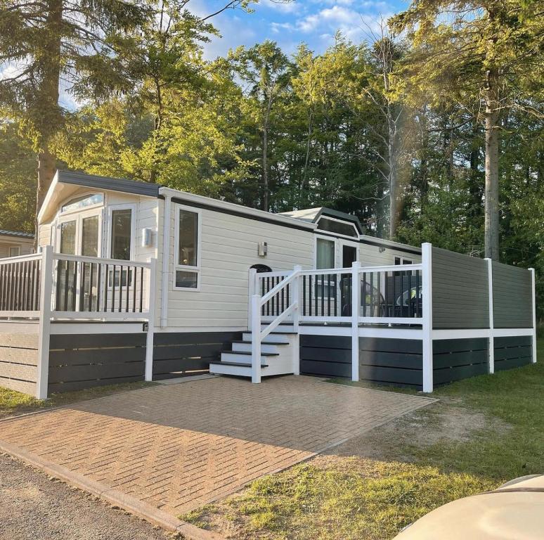 a tiny house with a porch and a deck at Percy Wood Lodges with Hot Tubs in Swarland
