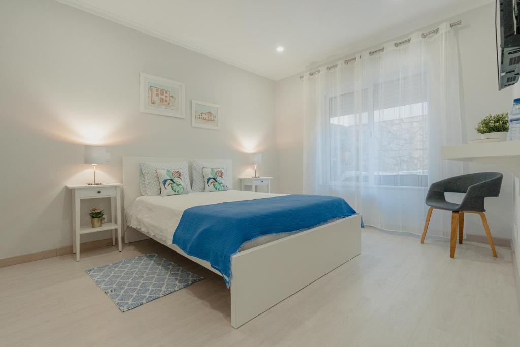 a white bedroom with a bed and a chair at 20 da Vila - Messines Valley in São Bartolomeu de Messines