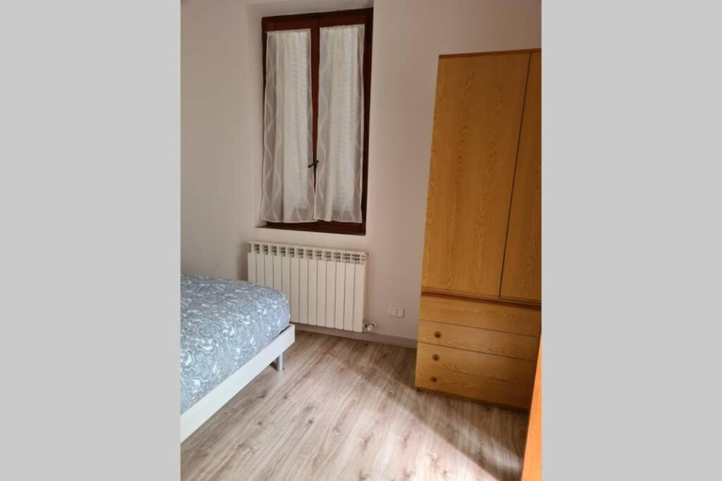 sypialnia z łóżkiem, komodą i oknem w obiekcie Tranquillo Appartamento in piazza w mieście Grosseto