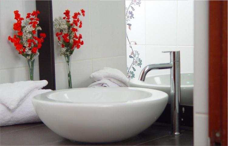 a bathroom with a white bowl sink and vases with flowers at Hotel Boulevard Plaza in Pucallpa