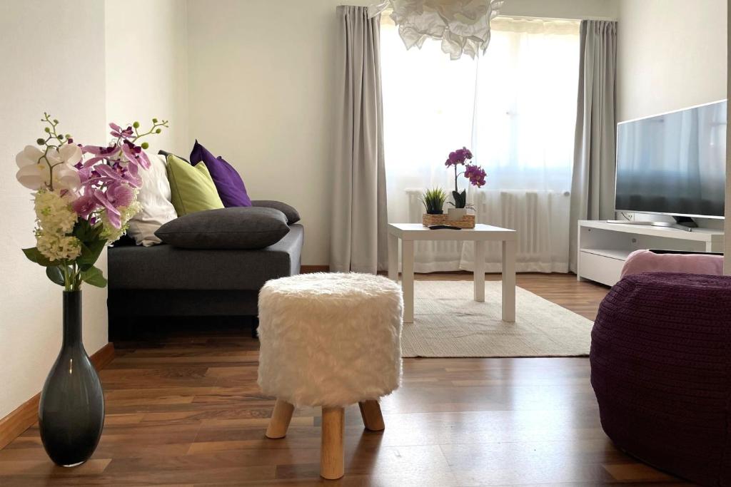 a living room with a couch and a vase of flowers at Modern apartment in a charming old town setting in Altstätten