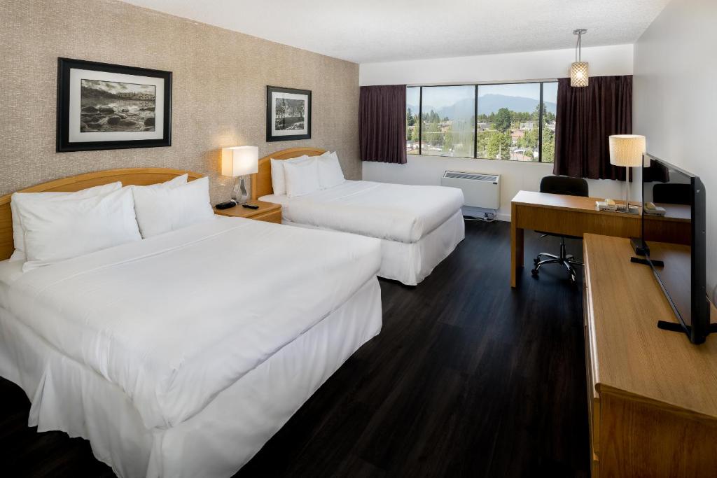 Habitación de hotel con 2 camas y escritorio en Cassandra Hotel, en Vancouver