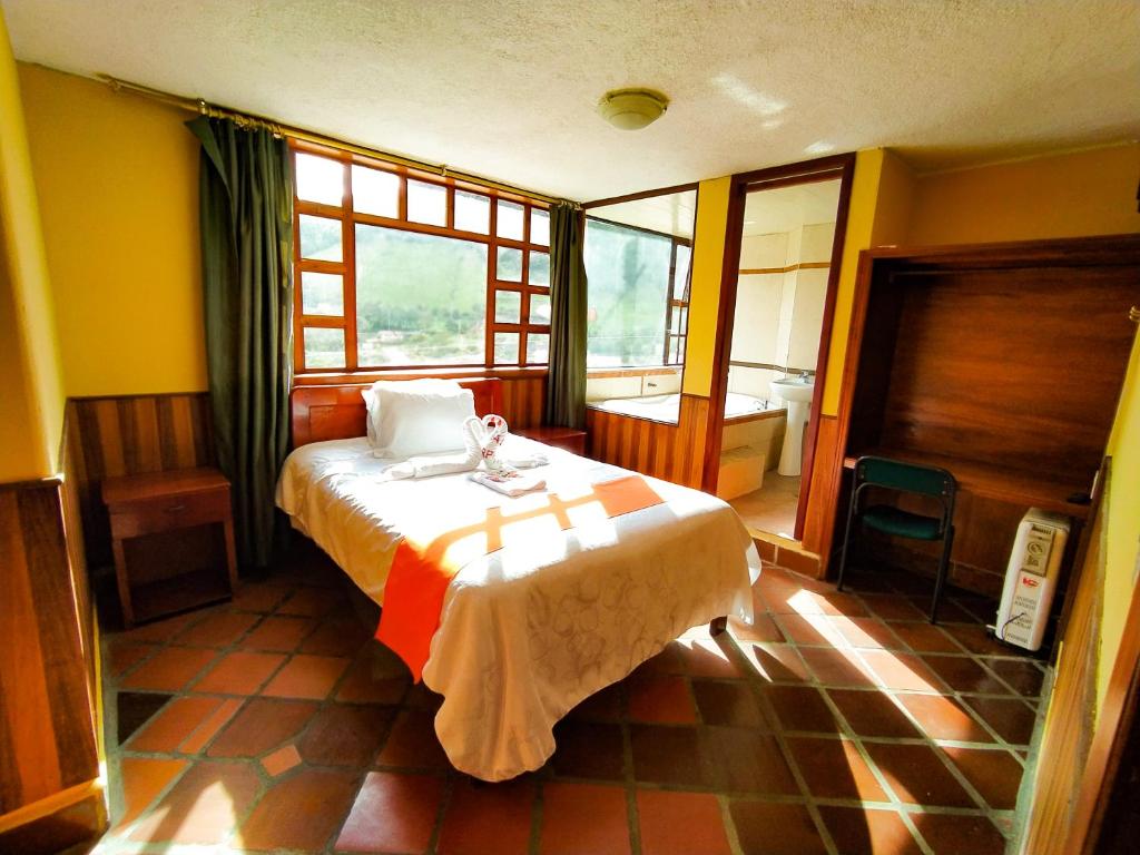 a bedroom with a bed in a room with windows at Hotel COTURPA in Papallacta