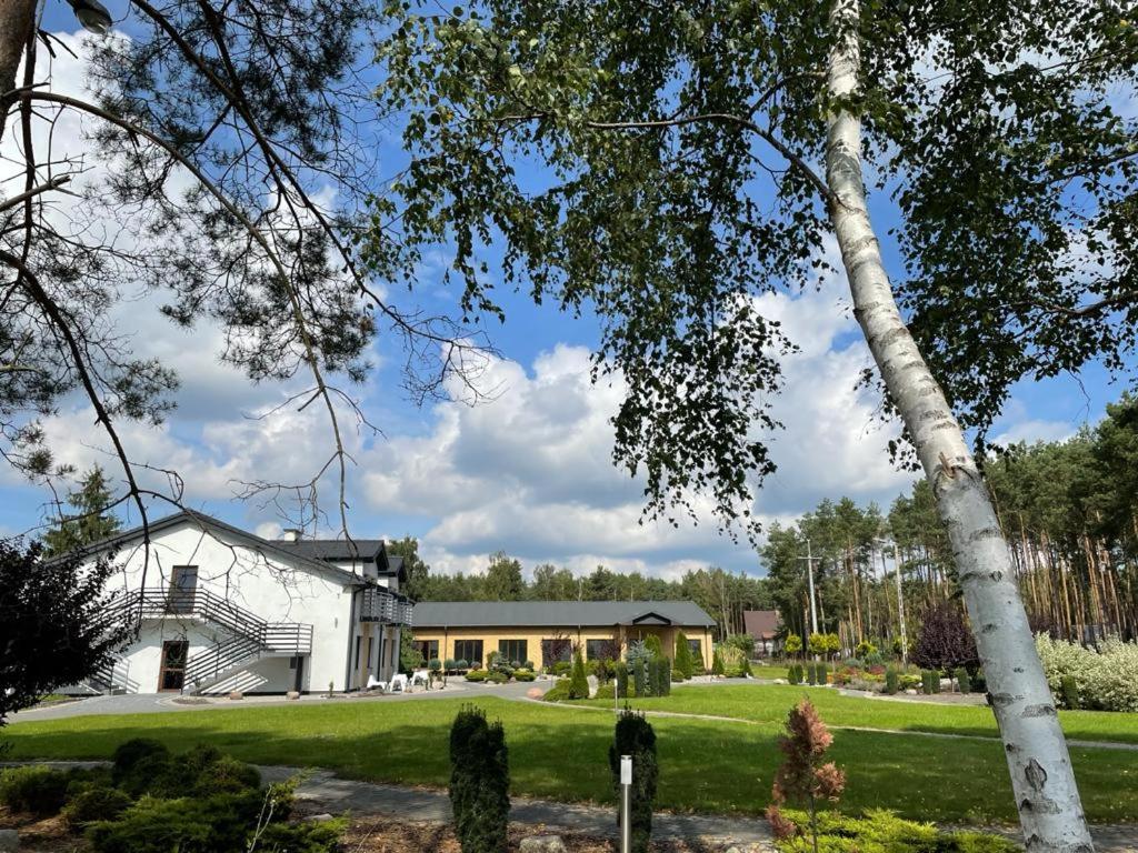 uma casa branca com uma árvore em frente em ZIELONA19 NOCLEGI em Zielonka