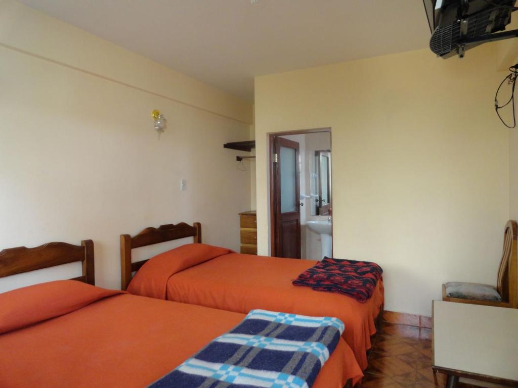 a bedroom with two beds and a bathroom at Concordia - Hospedaje in Cochabamba