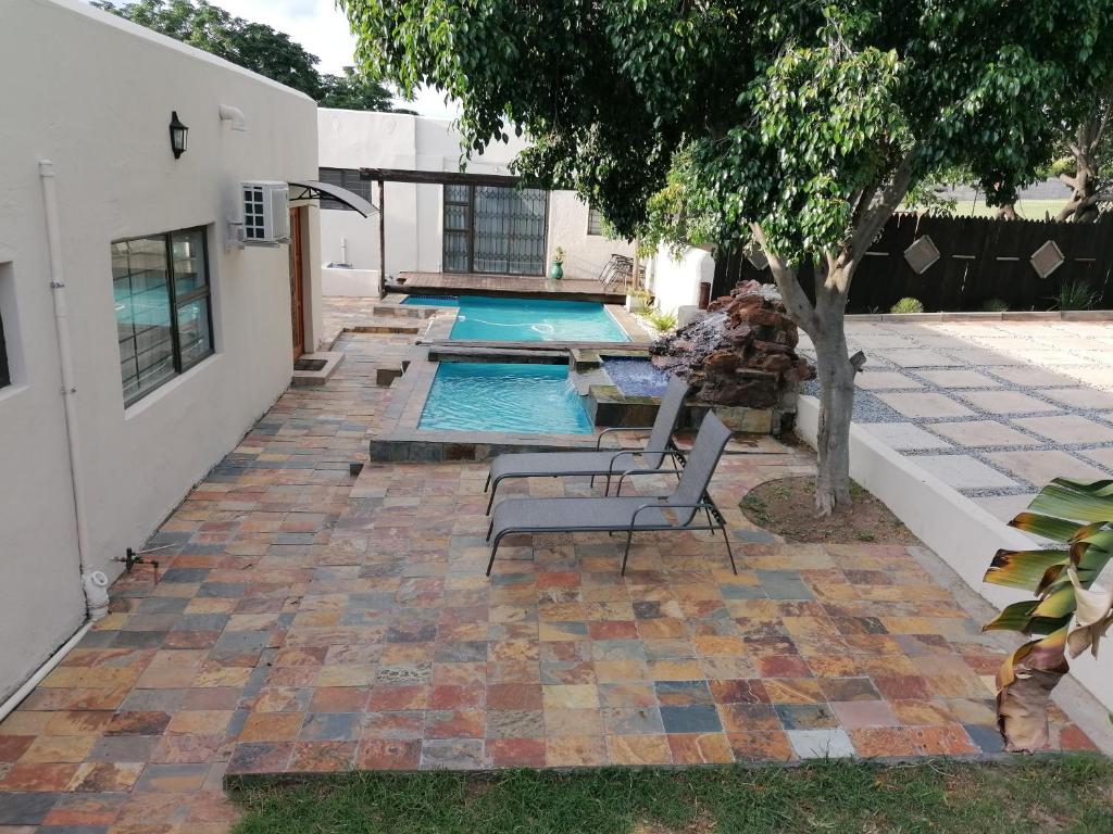 a patio with a pool with a bench and a tree at JB Countrylife Accommodation in Centurion