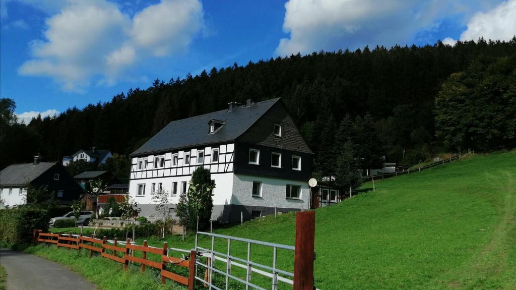 a large white house on a hill with a fence at FeWo im schönen Sauerland in Meschede