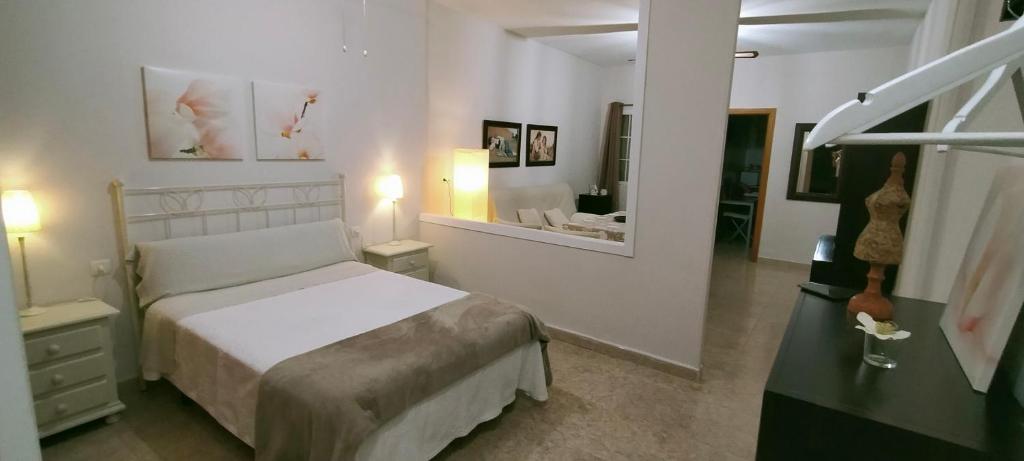 a white bedroom with a bed and a mirror at Castella Aquae estudio in Mérida