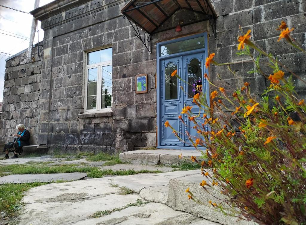 a person sitting on a bench in front of a brick building at Konjelazia - Tourism & Design in Gyumri