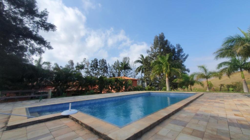 a swimming pool in a villa with palm trees at Pousada das Casuarinas in Paty do Alferes
