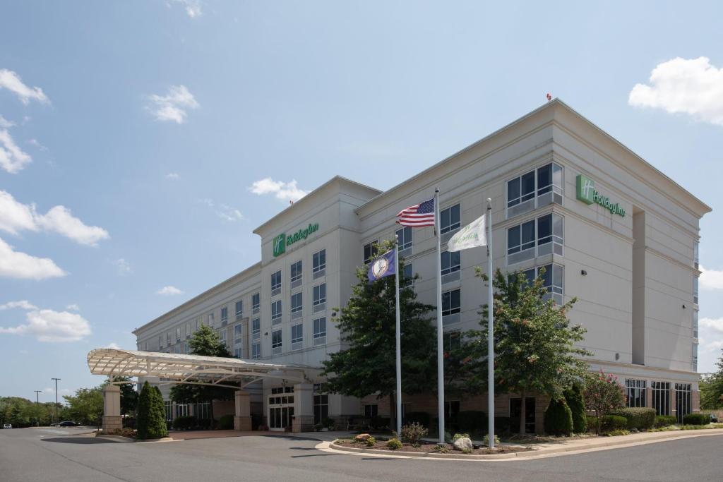 Um edifício de escritórios com uma bandeira americana à frente. em Holiday Inn Winchester Southeast-Historic Gateway, an IHG Hotel em Winchester