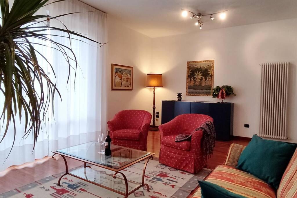 Diamante: Appartamento nel cuore della Toscana في Castelfranco di Sotto: غرفة معيشة مع كرسيين حمر وطاولة زجاجية
