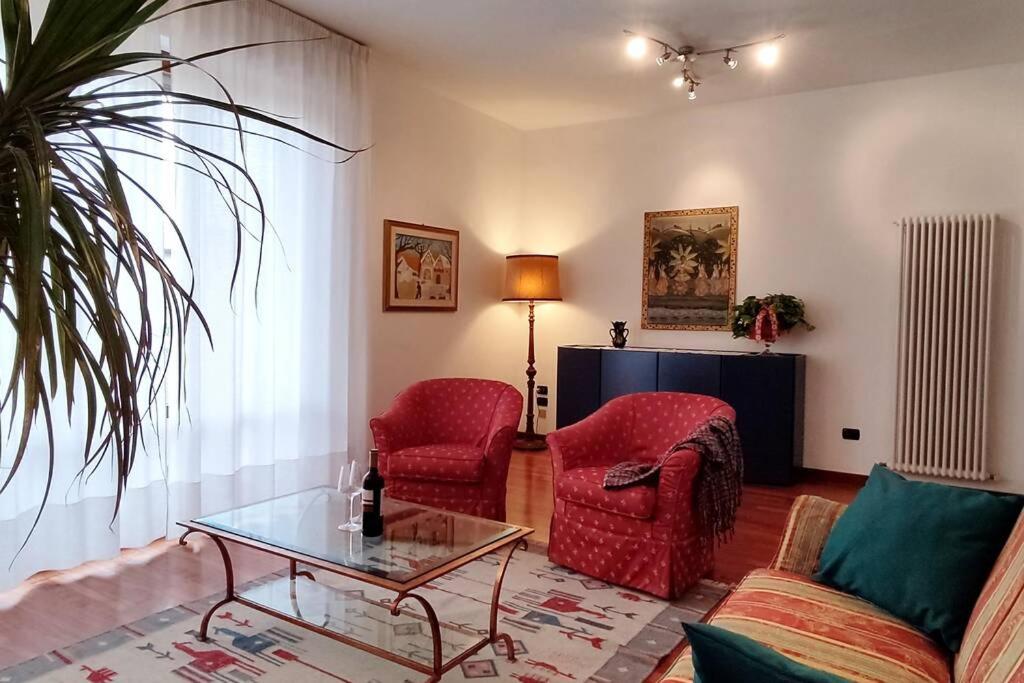 a living room with two red chairs and a glass table at Diamante: Appartamento nel cuore della Toscana in Castelfranco di Sotto