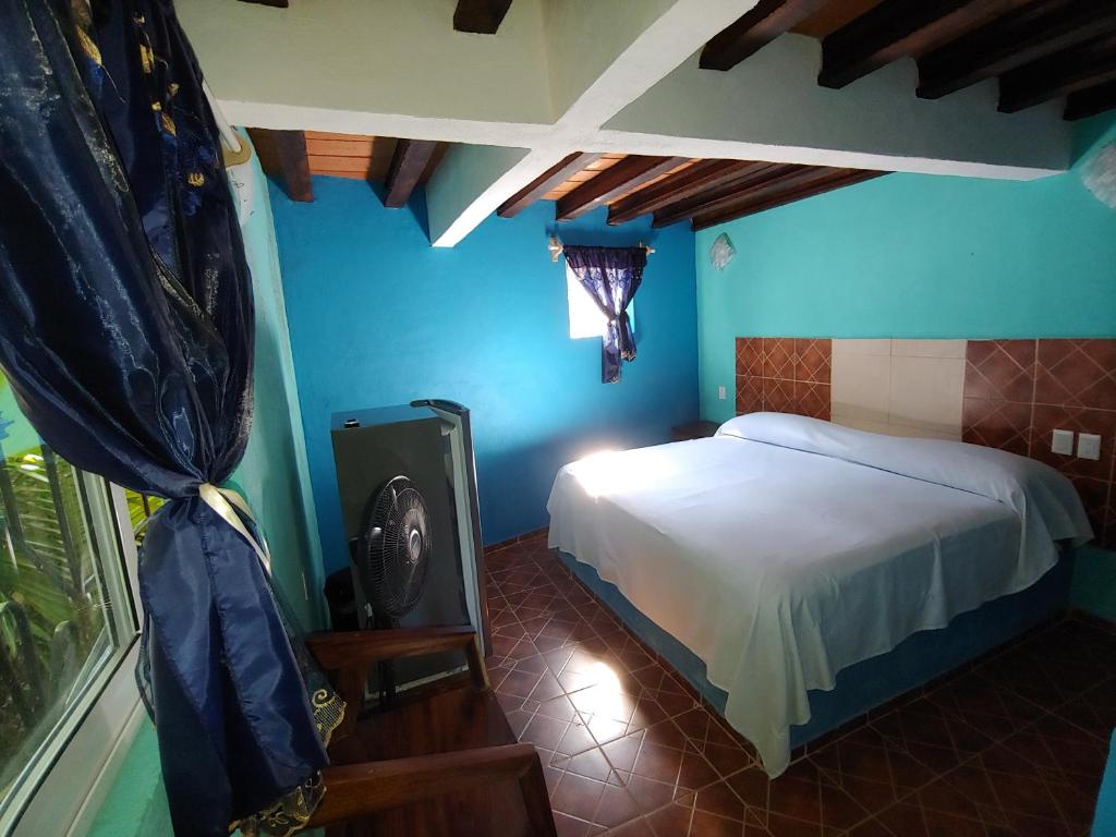 - une chambre avec des murs bleus, un lit et une fenêtre dans l'établissement CASA NANTLI, à Yelapa