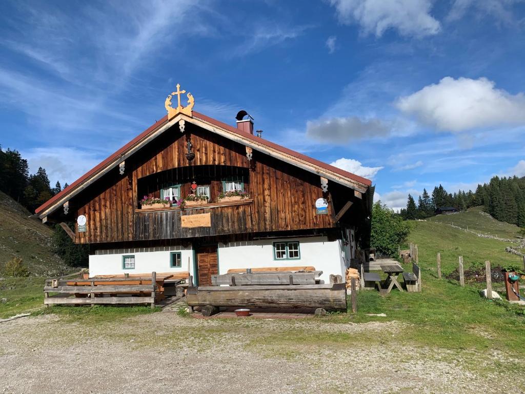 a large wooden building in the middle of a field at Rettenbäckalm in Schliersee