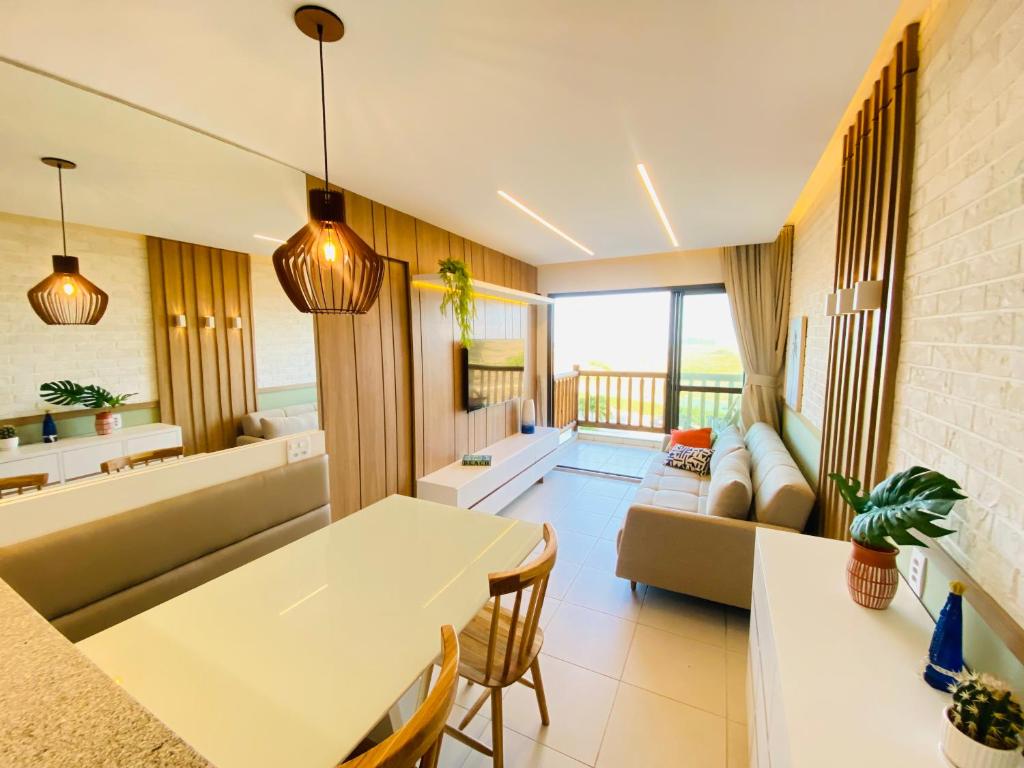 uma sala de estar com uma mesa e um sofá em Apartamento luxo no VG SUN Cumbuco com vista para o mar em Cumbuco