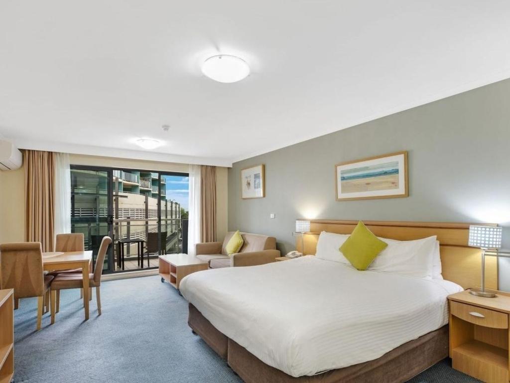 Una habitación de hotel con una cama grande y un escritorio. en Waterfront Apartment 216, en The Entrance