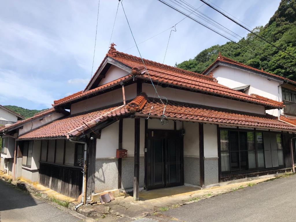 una pequeña casa con techo rojo en 古月(KozukI)久年庵 en Yamaguchi