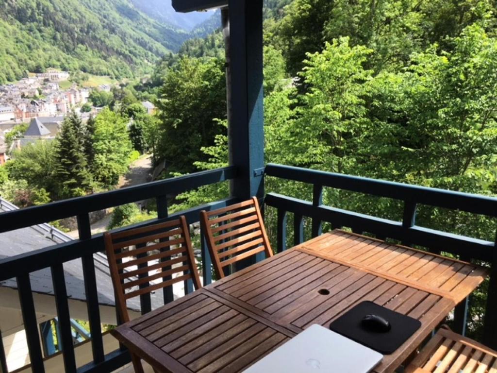 d'une table et de chaises en bois sur un balcon avec vue. dans l'établissement Appartement 6 pers. avec terrasse - 3 Pièces 6 personnes MAE-9108, à Cauterets