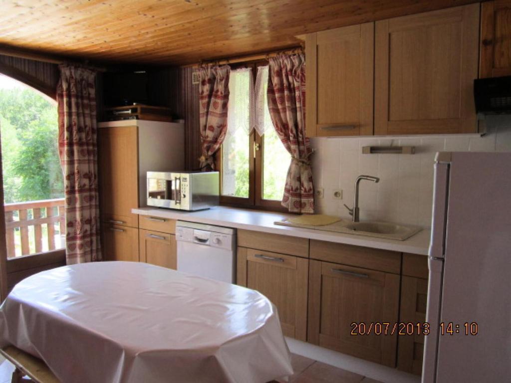 a kitchen with a table and a white refrigerator at Appartement 6 pers. avec vue montagne - 3 pièces 5 personnes MAE-0672 in Saint-Sorlin-dʼArves