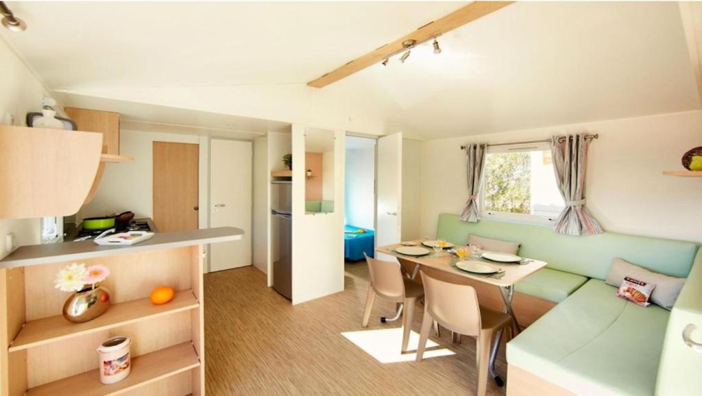 Il dispose d'une cuisine et d'un salon avec une table et un canapé. dans l'établissement Mobil-home 4 pers. proche plage - Mobil-home 3 Pièces 4 Personnes MAE-8963, à Saint-Jean-de-Monts