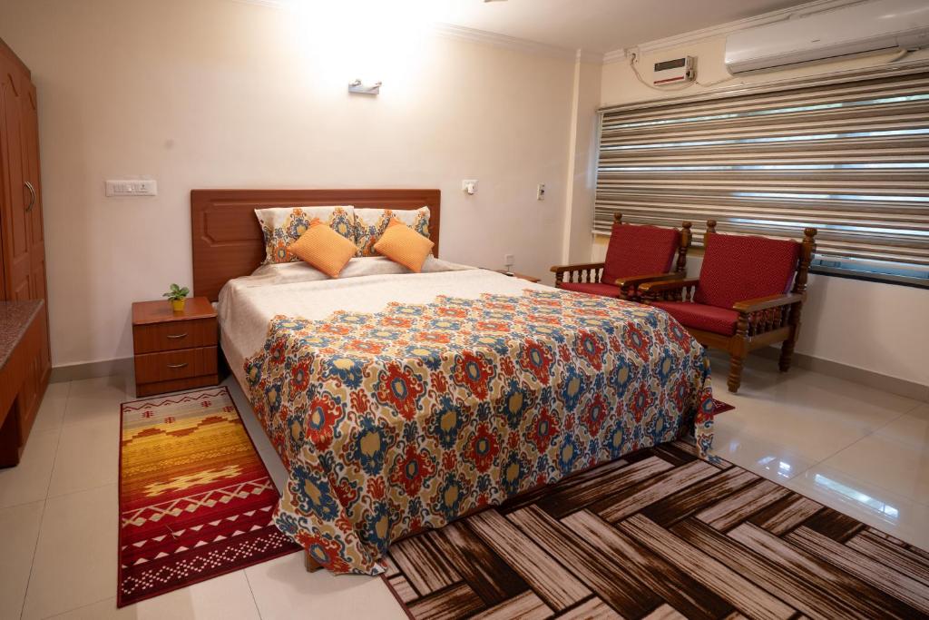 a bedroom with a large bed and two red chairs at Hotel TamilNadu, Madurai II in Madurai