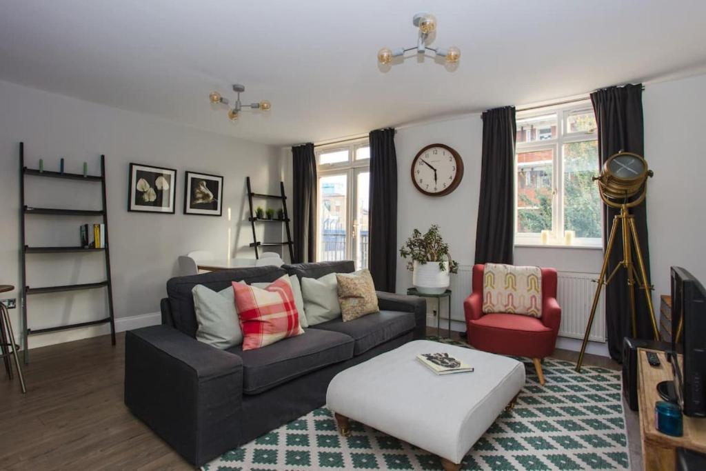 un soggiorno con divano, tavolo e orologio. di Lovely 2 Bedroom Flat near Whitechapel Station a Londra
