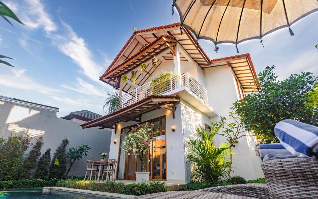 a house with an umbrella next to a pool at The Kailas Ubud in Ubud