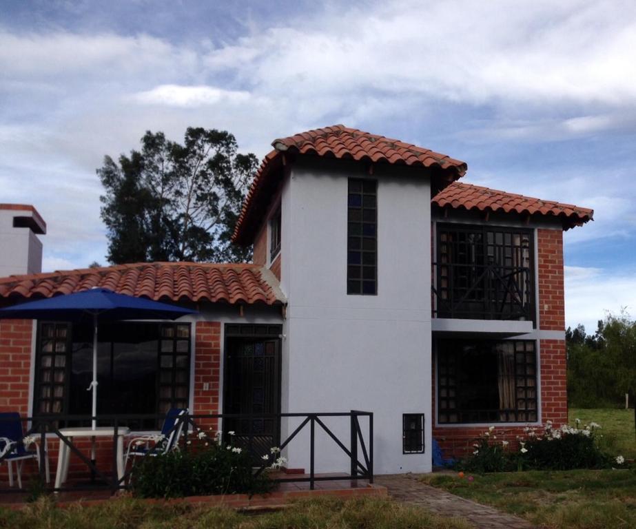 a white house with a red roof at Cabaña Campestre El Refugio in Paipa