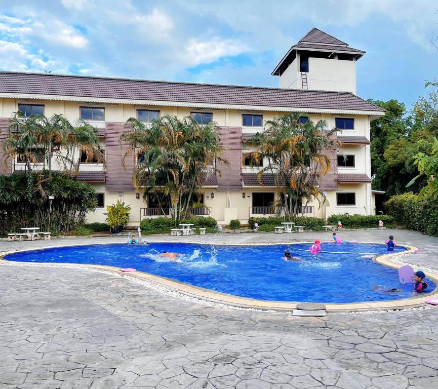 uma piscina em frente a um hotel com pessoas nele em Luckswan Resort Chiang Rai - SHA Extra Plus em Chiang Rai