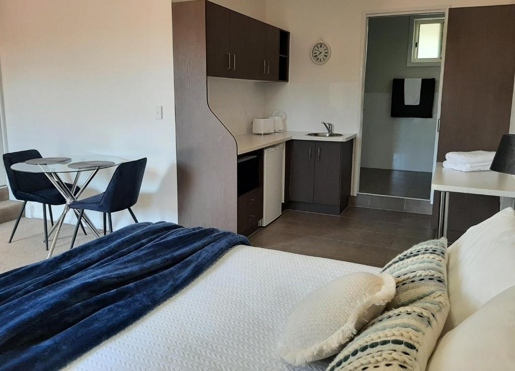 a bedroom with a bed and a kitchen and a table at Tourist Road - Studio Unit - Wi-Fi in Toowoomba