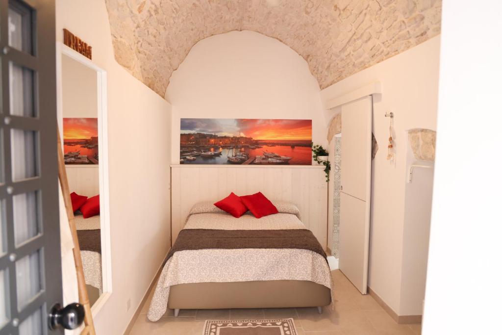 - une petite chambre avec un lit et des oreillers rouges dans l'établissement Room 20 - Piccola Camera in pietra bianca, à Giovinazzo