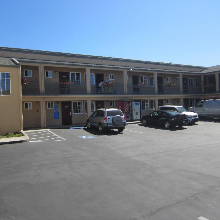 a building with cars parked in a parking lot at Pacific Best Inn in Seaside