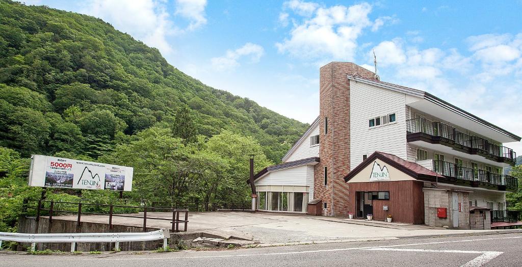 a building on the side of a road next to a mountain at Tenjin Lodge in Minakami