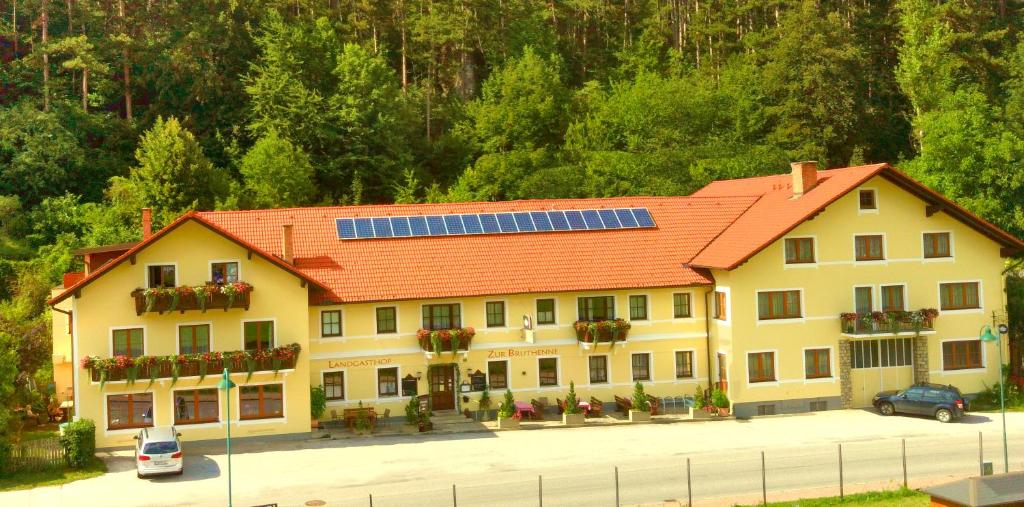 un grand bâtiment jaune avec un toit orange et des panneaux solaires dans l'établissement Gasthof zur Bruthenne, à Weissenbach an der Triesting