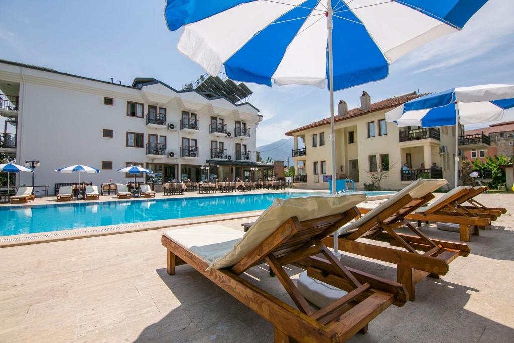 a group of chairs and umbrellas next to a swimming pool at Kilim Hotel & Apart in Fethiye