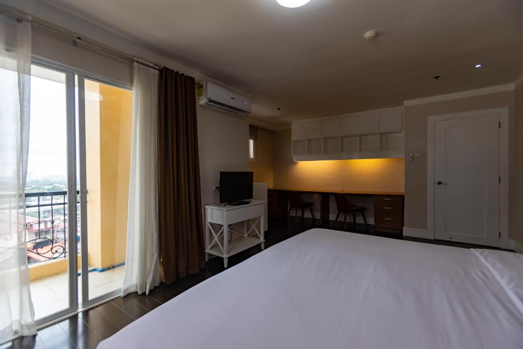 a bedroom with a large white bed and a kitchen at Sta Barbara Residence Hotel in Cebu City
