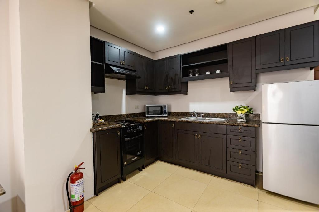 a kitchen with black cabinets and a white refrigerator at Sta Barbara Residence Hotel in Cebu City