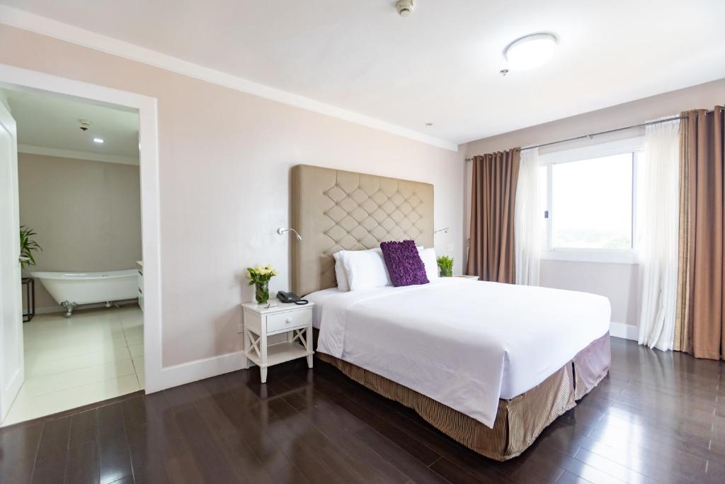 a bedroom with a large bed and a bath tub at Sta Barbara Residence Hotel in Cebu City