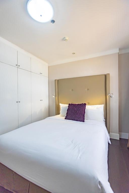 a bedroom with a large white bed with a purple pillow at Sta Barbara Residence Hotel in Cebu City