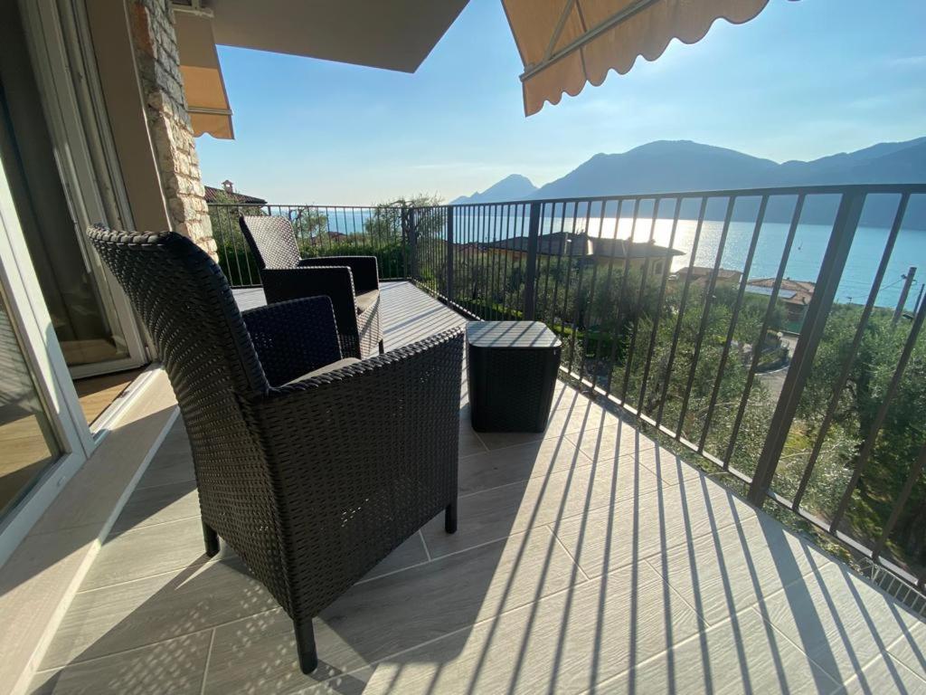 een balkon met rieten stoelen en een tafel en de oceaan bij Villalvento in Brenzone sul Garda