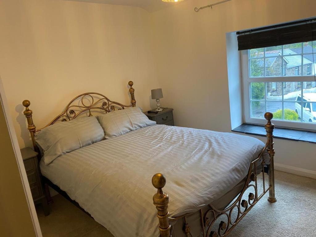 a bedroom with a large bed with a window at 2-Bed Cottage in in Welsh Valley Nr Swansea in Swansea