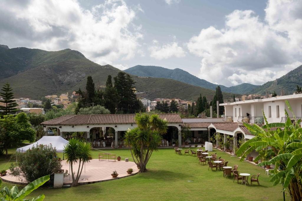 a resort with tables and chairs and mountains in the background at Hotel Domu Incantada in Muravera