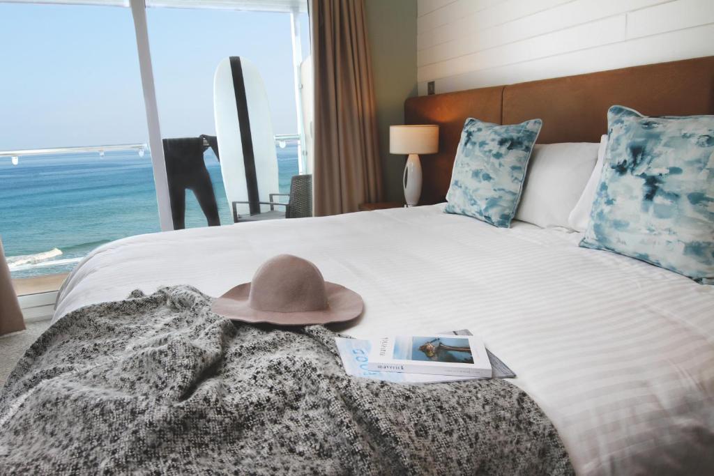 a hat on a bed with a view of the ocean at Esplanade Hotel in Newquay